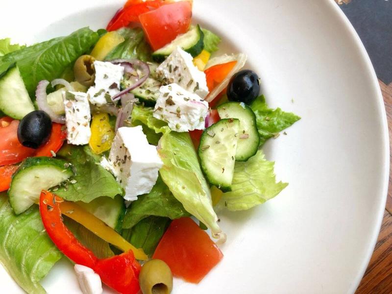 Close-up of a plate of mixed green vegetables salad with capsicum, cheese and olives